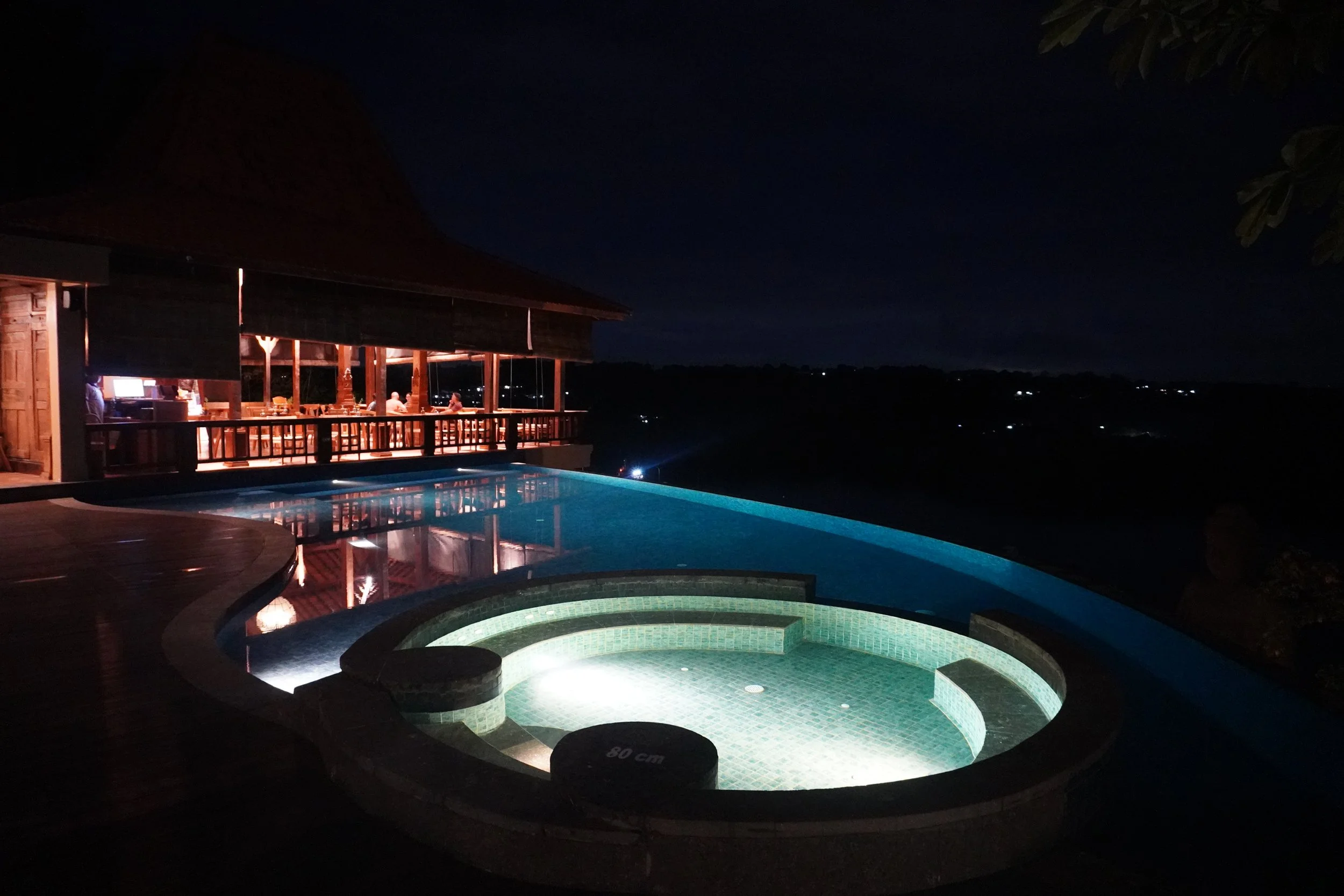 Infinity pool illuminated at night overlooking the coastline and tropical surroundings