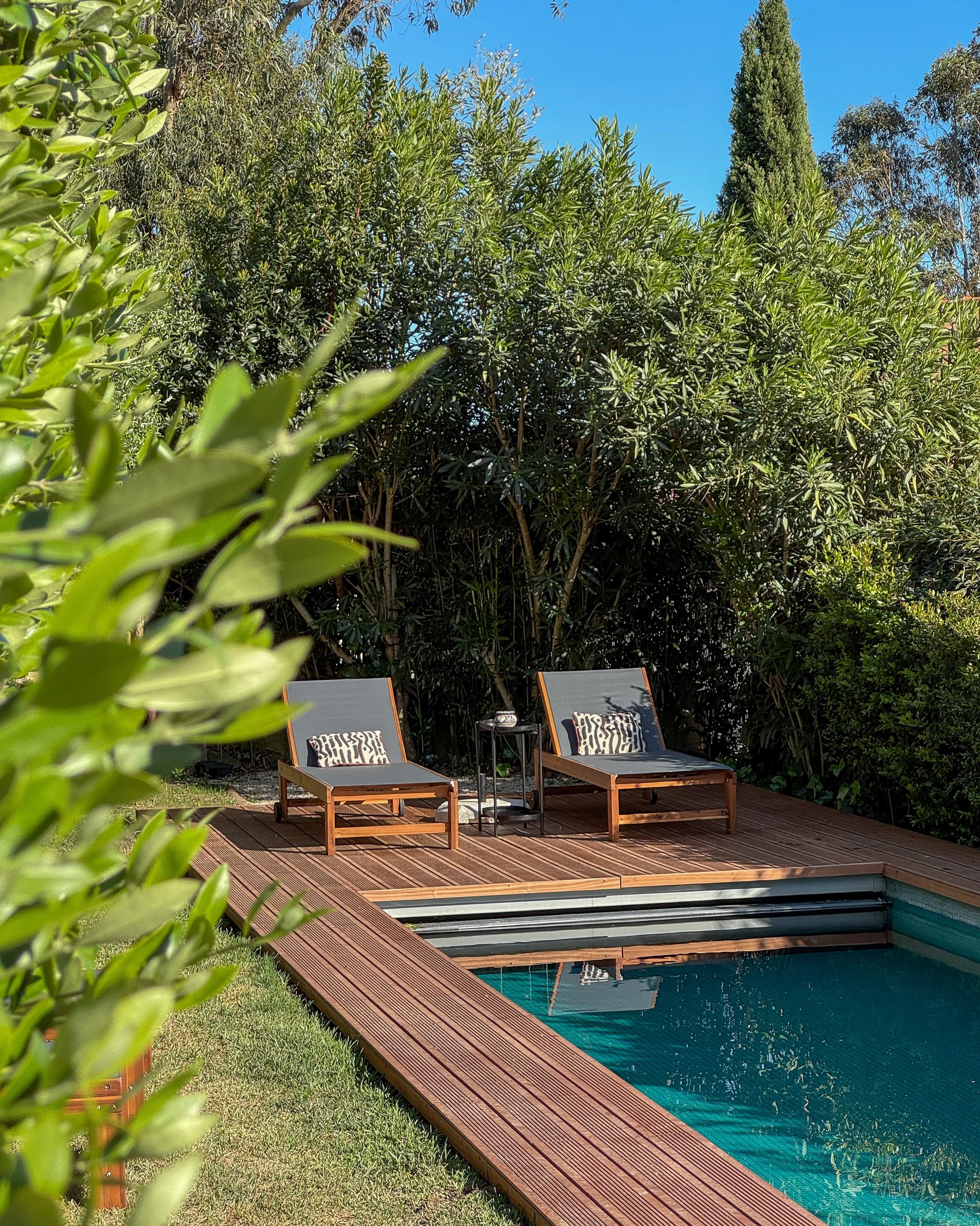 Private pool surrounded by greenery and wooden deck lounge area at Dream Guincho