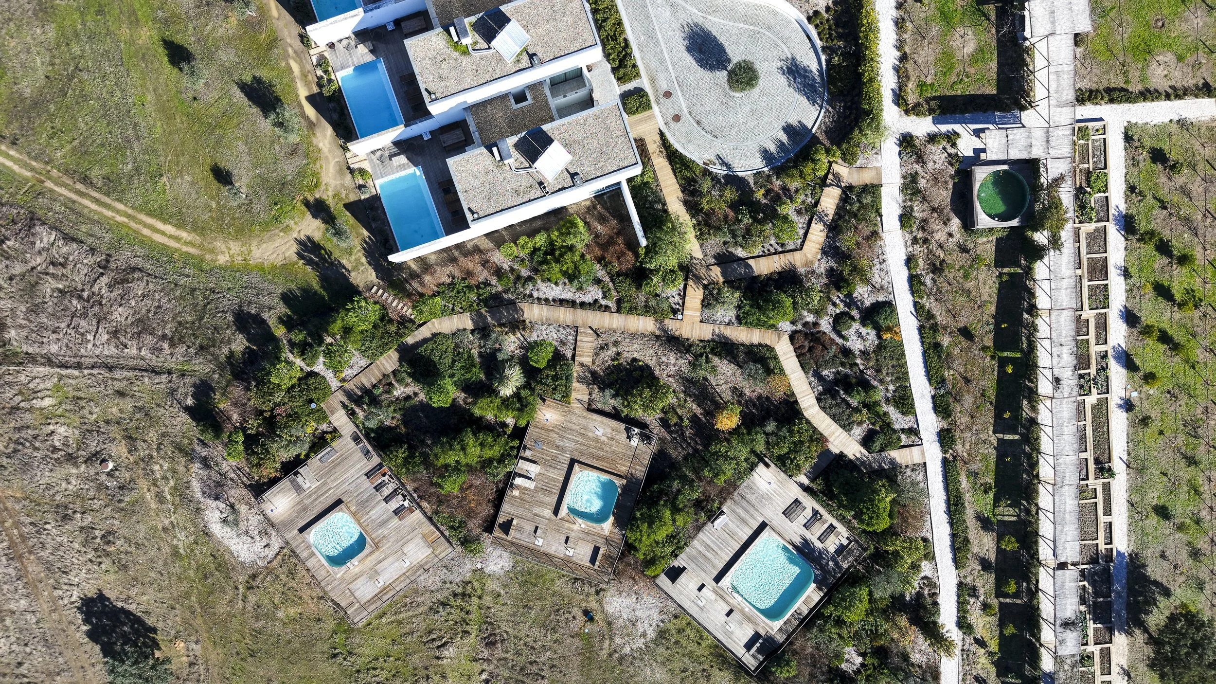 Top-down aerial view of private plunge pools connected by wooden walkways and native Alentejo landscaping — Octant Évora