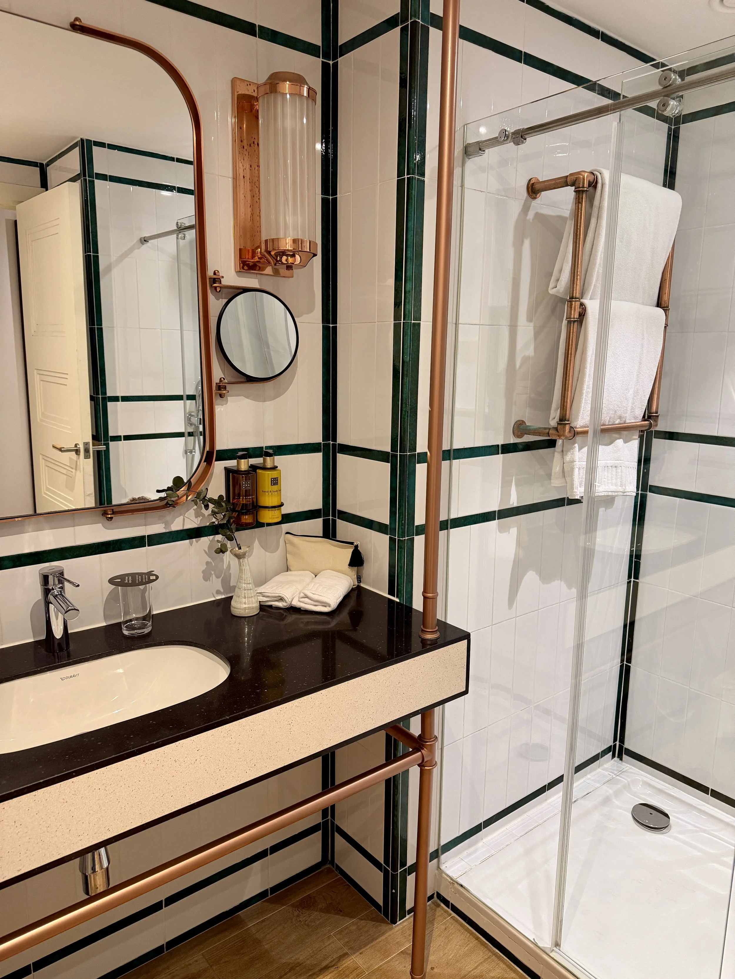 Contemporary bathroom featuring copper accents, premium amenities, and elegant geometric tile details