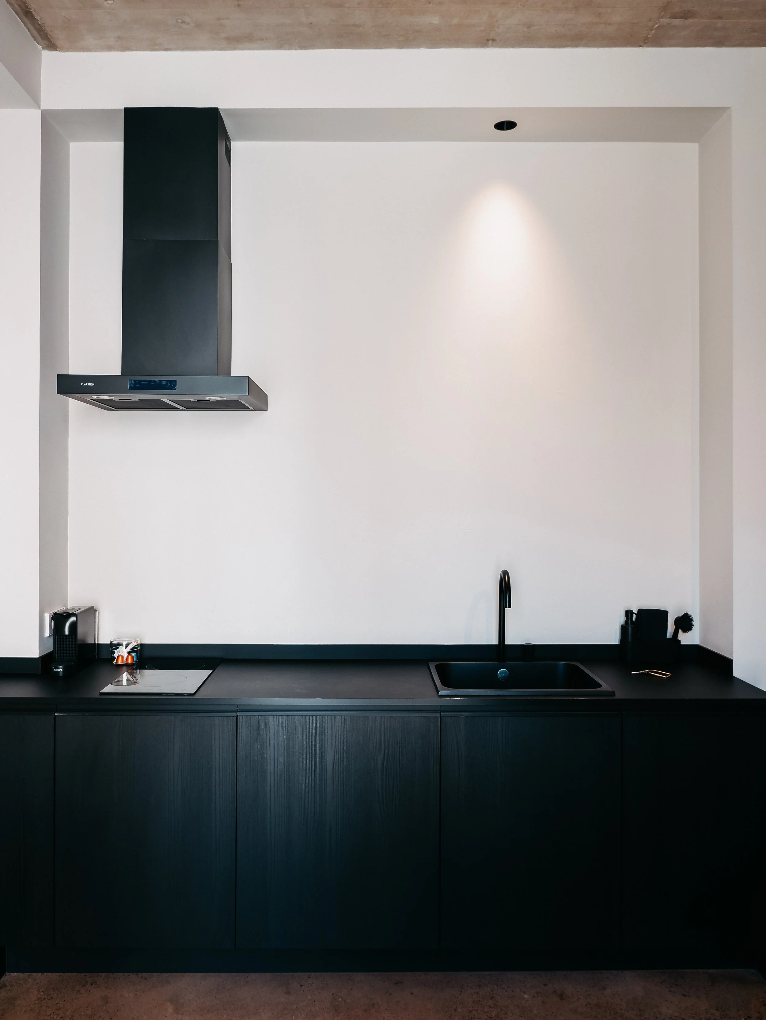 Contemporary kitchenette with sleek black cabinetry and minimalist design details
