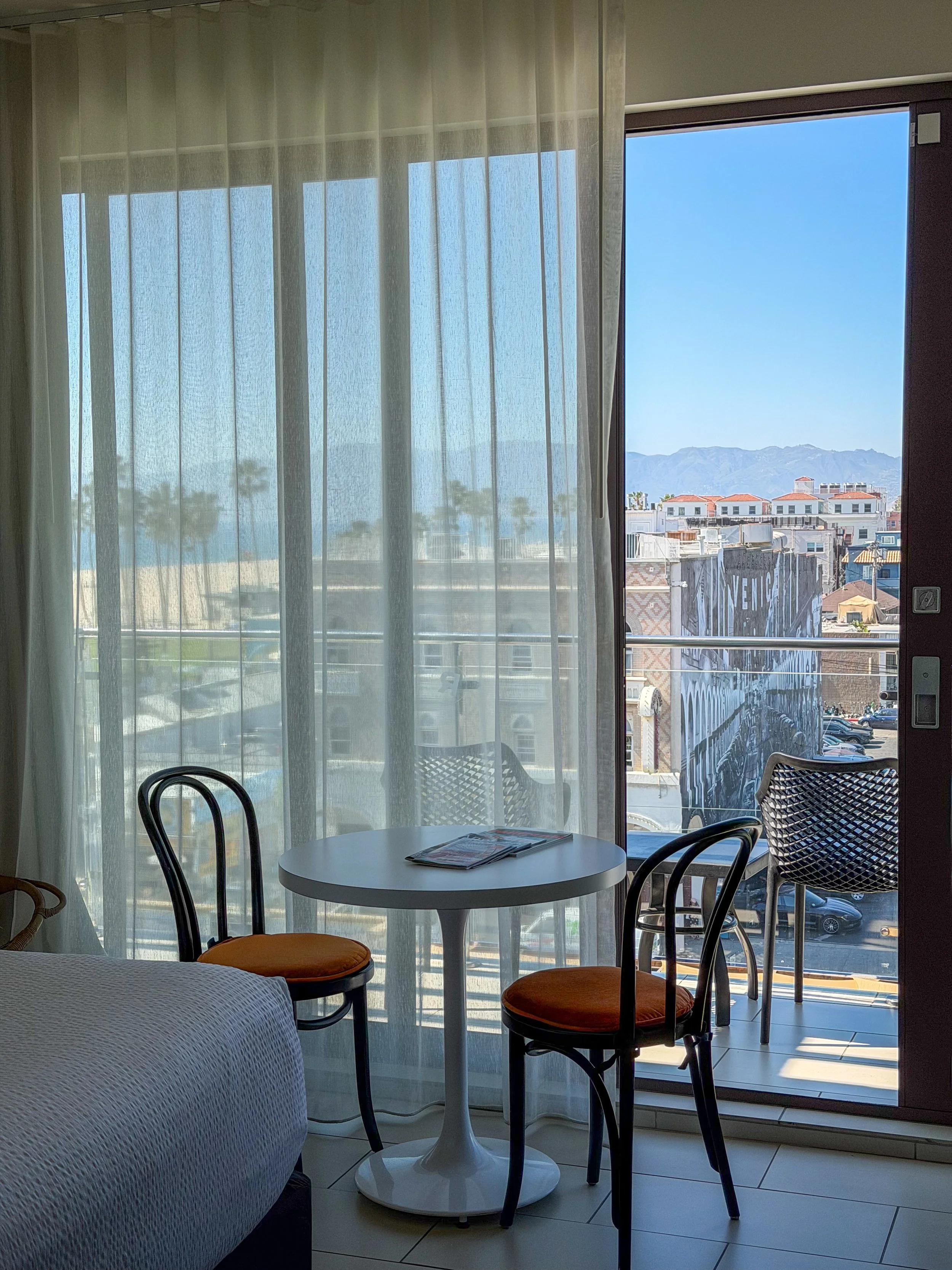 Bright guest room with floor-to-ceiling windows, private balcony, and sweeping coastal views
