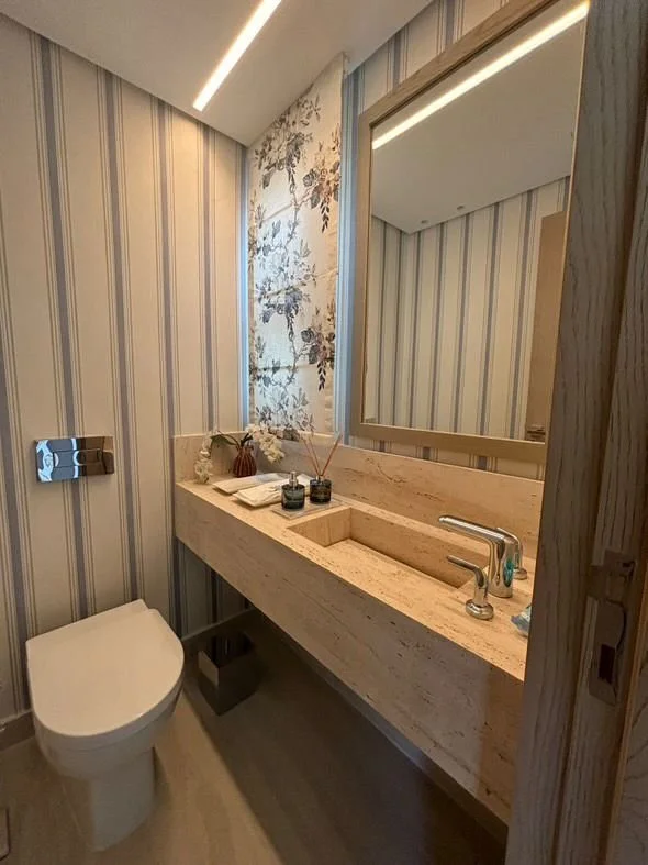 Lavabo monolitico in travertino con rubinetteria essenziale e dettagli decor coordinati.