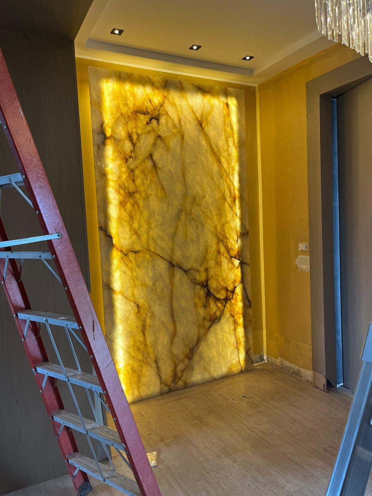 Hall d'ingresso con parete in onice con illuminazione LED nascosta che accentua le venature naturali della pietra. 