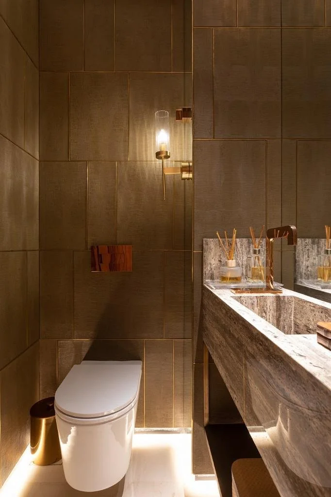 Lavabo in marmo con maxi specchio e illuminazione radente: atmosfera intima e sofisticata.