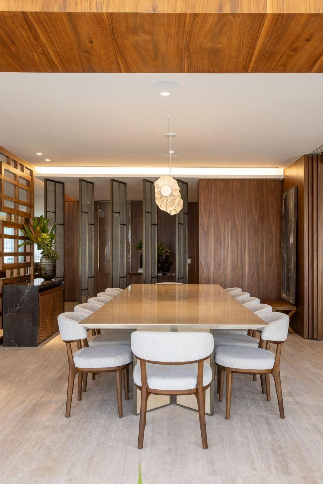Ingresso materico con boiserie in legno e luce radente che valorizza le venature.