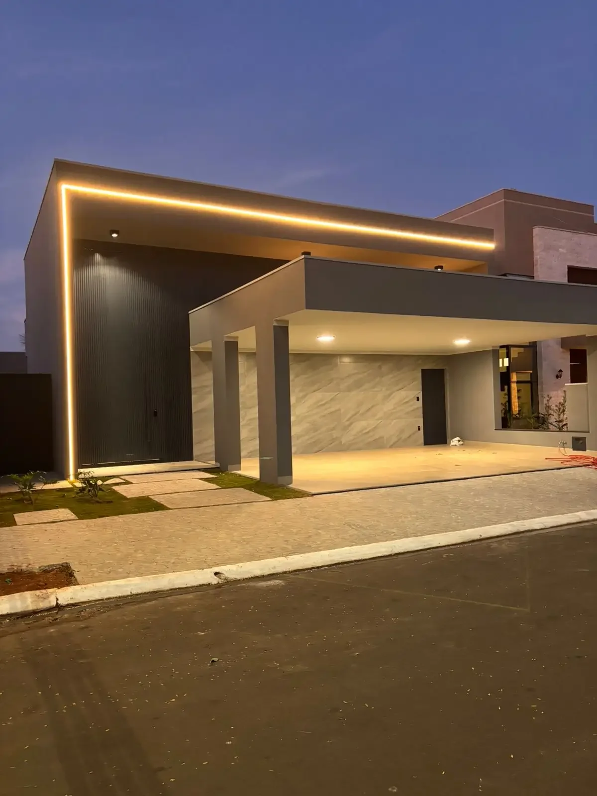 La costruzione ultimata rivela il carattere deciso della facciata in grigio antracite. Una visione notturna dei tagli luminosi che non solo illuminano ma scolpiscono i volumi. 