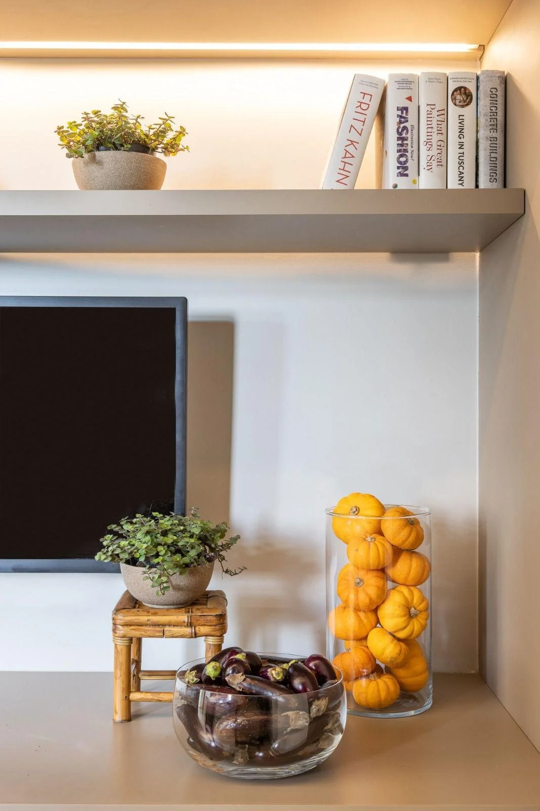 Dettaglio decor su mensola: libri, verde e composizioni cromatiche in equilibrio.
