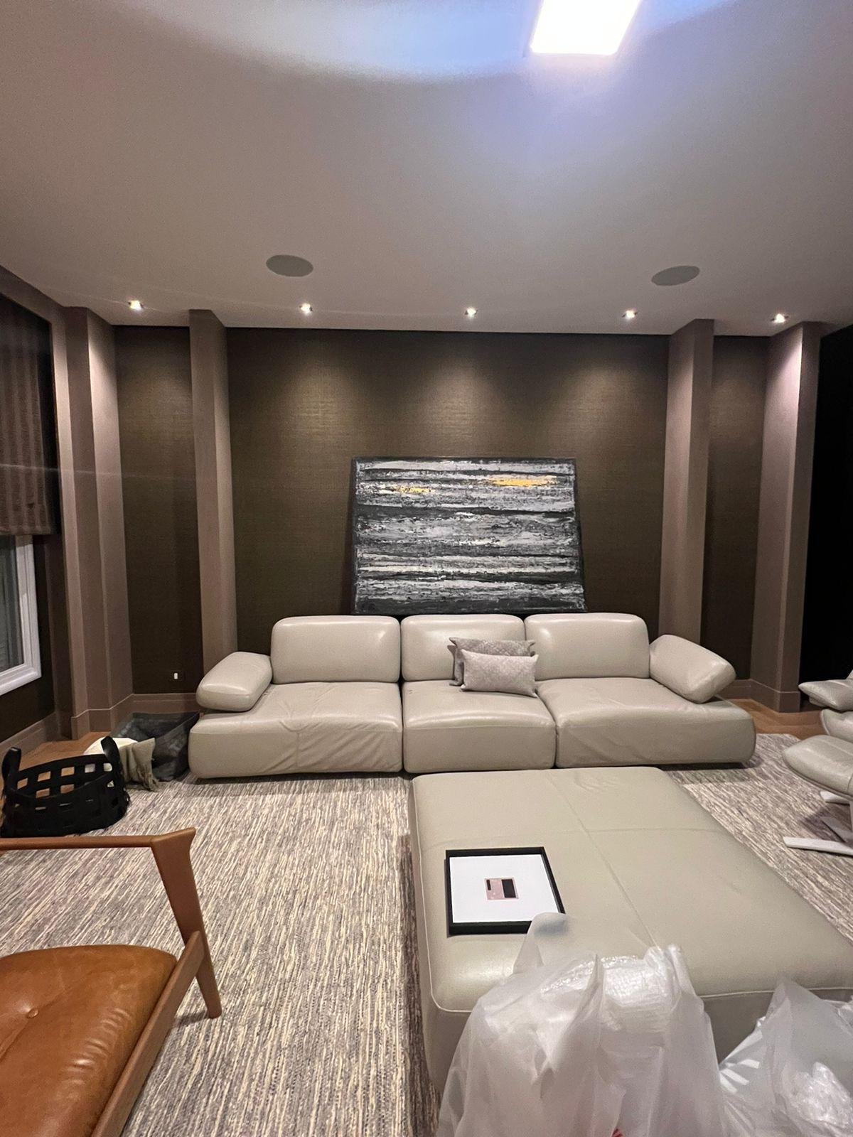 Divano in pelle chiara e pareti decorate da un'opera d'arte contemporanea. 