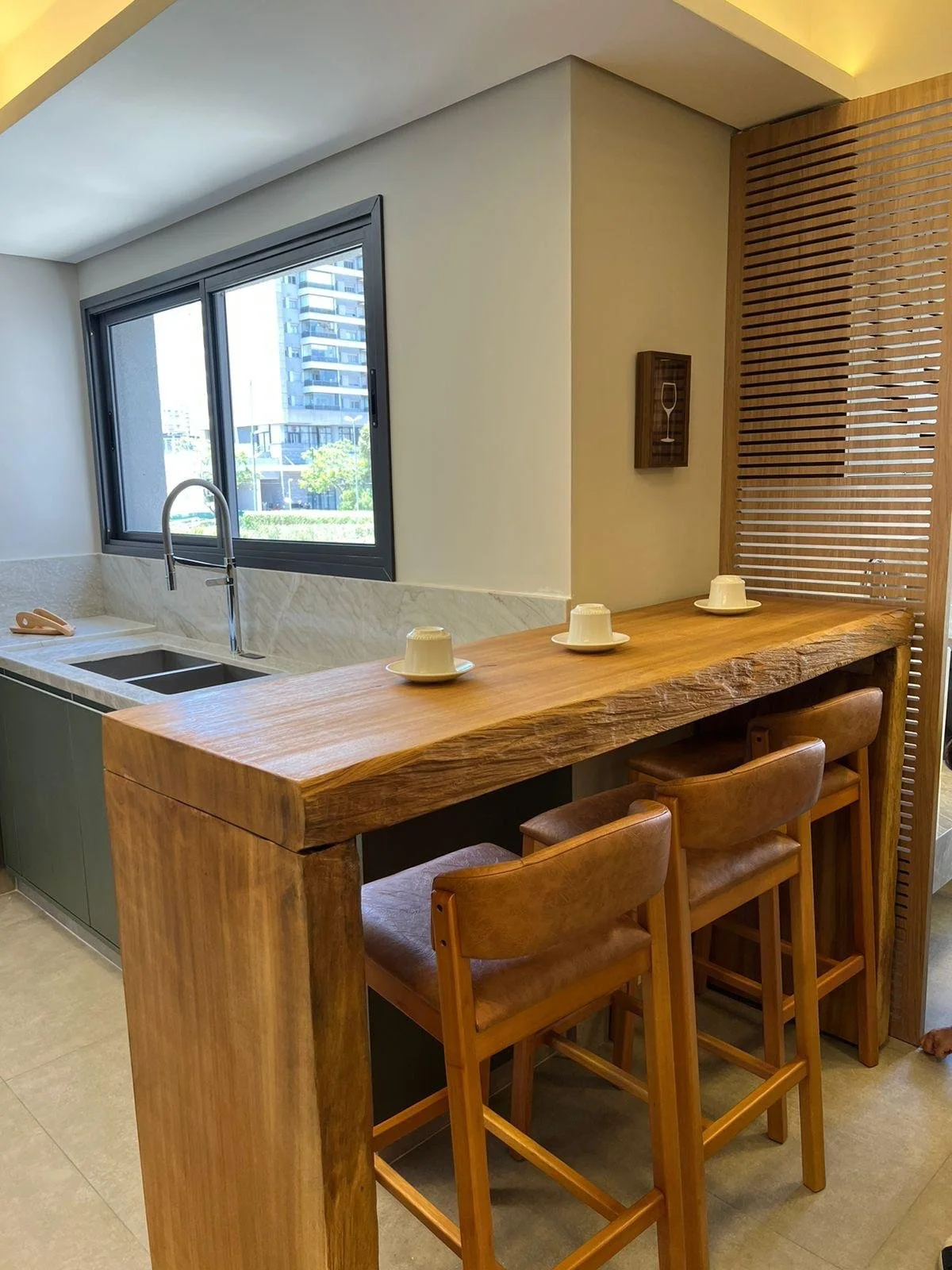 Cucina americana integrata con tavolo alto in legno massiccio e sgabelli in pelle. 