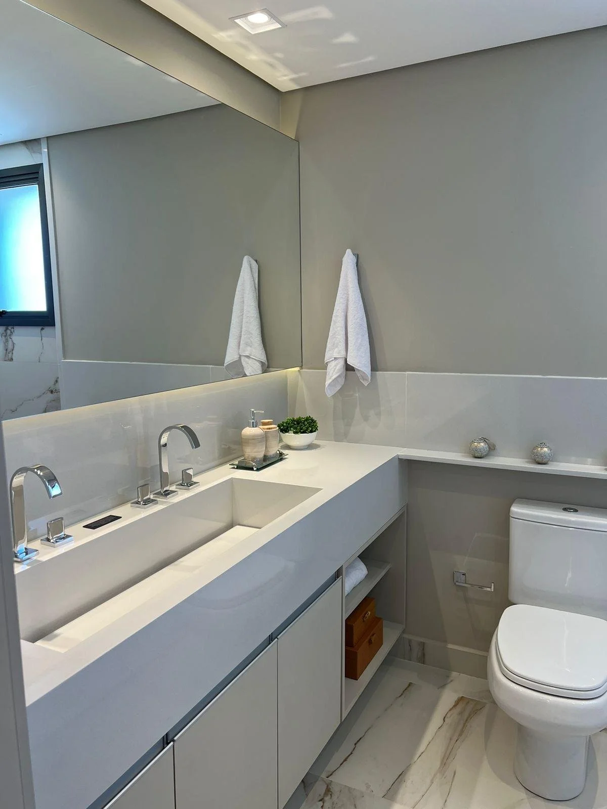 Bagno della stanza matrimoniale con sanitari moderni e illuminazione soffusa che esalta il design minimalista e elegante. L'ambiente è arricchito da dettagli in bianco e beige.