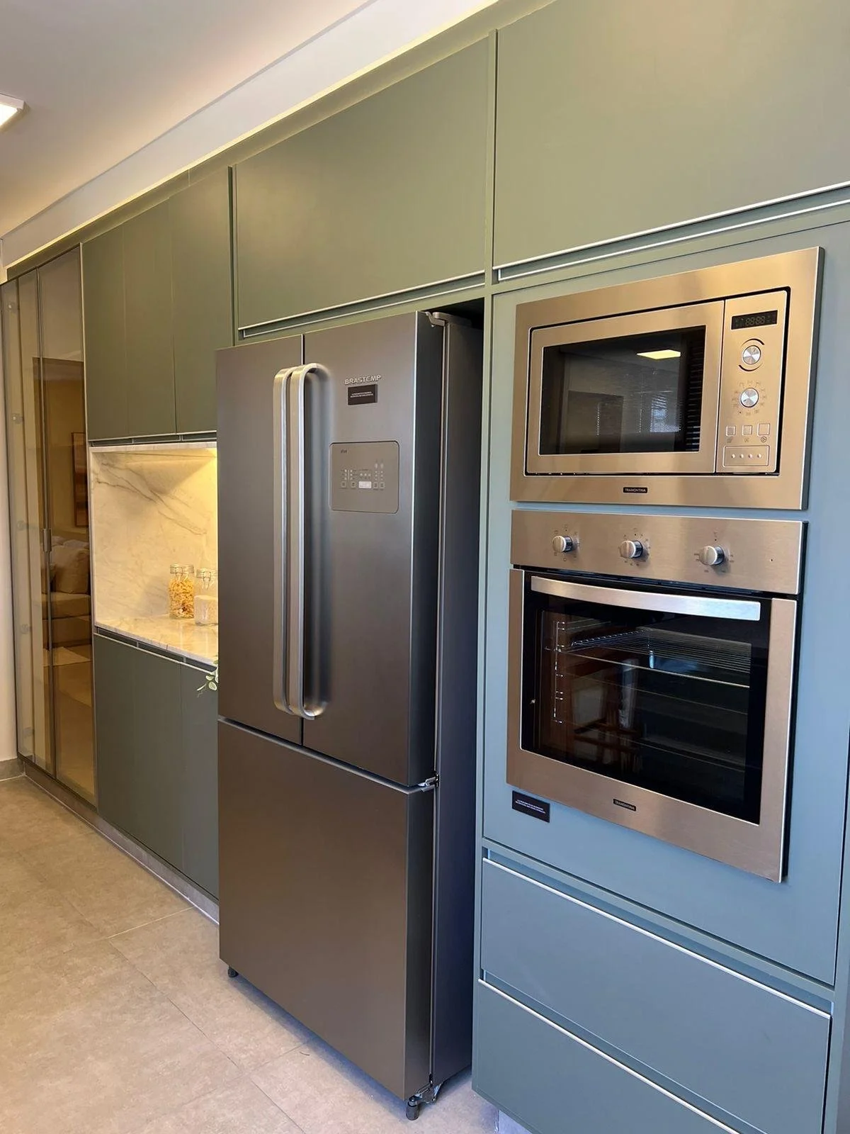 Elettrodomestici in acciaio inox e armadi su misura colore verdi opachi. 