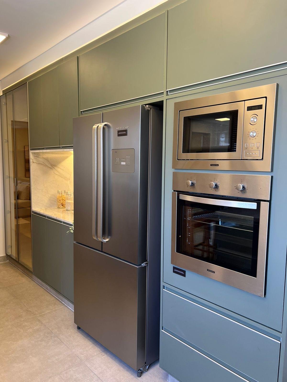 Elettrodomestici in acciaio inox e armadi su misura colore verdi opachi. 