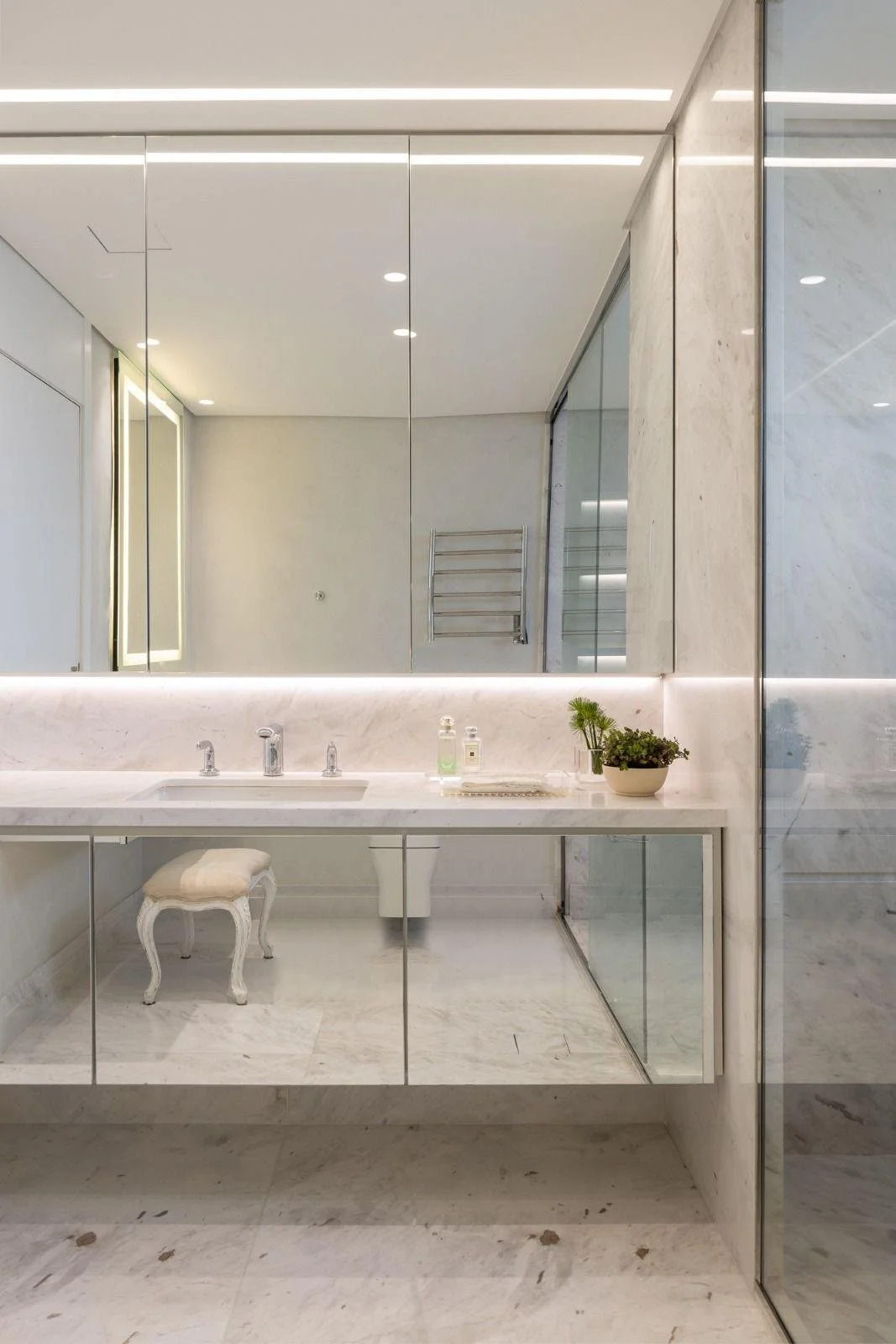 Bagno padronale in marmo con top sospeso e profili luminosi: minimal e luminoso.