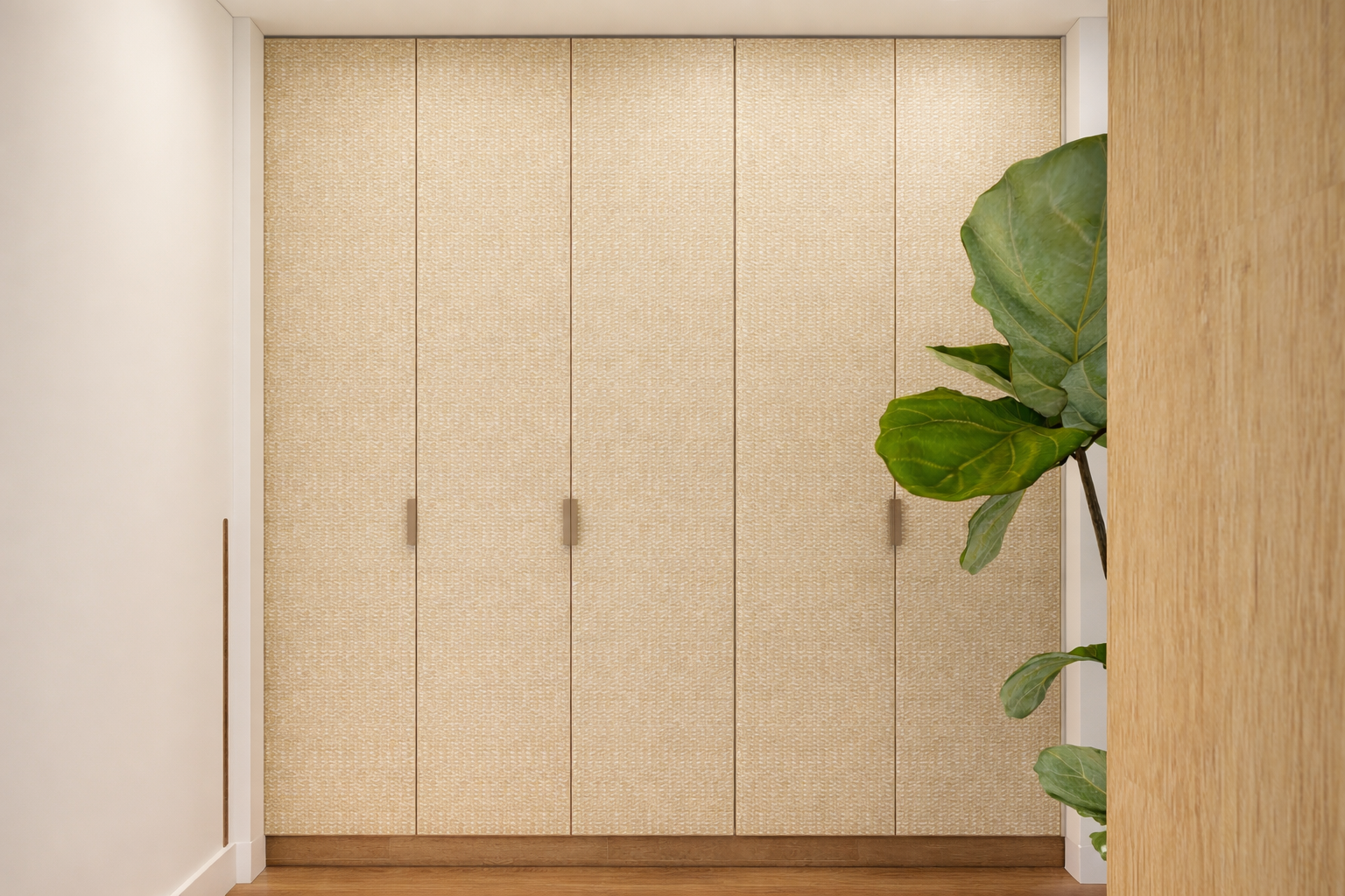 Armadio con ante in tessuto beige e maniglie dritte, accanto a pareti bianche e una pianta di grandi foglie verdi.
