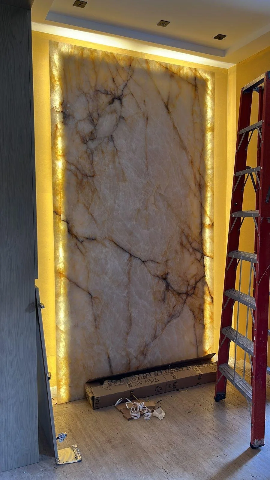 Questo elemento di design dona un aspetto lussuoso e raffinato agli spazi interni. L'illuminazione esalta le sfumature calde della pietra naturale.