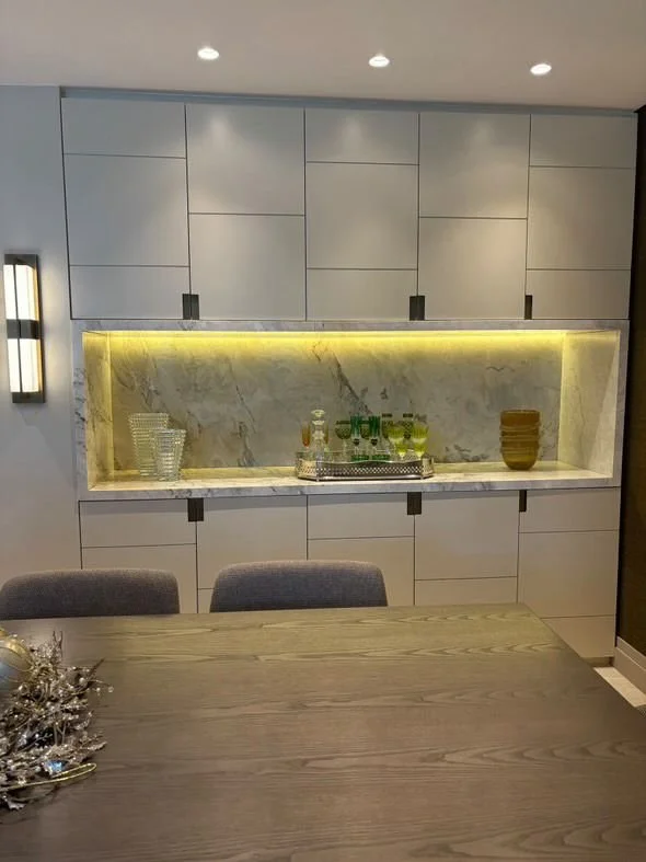 Vista frontale: nicchia in Calacatta a contrasto con le ante chiuse del mobile su misura, equilibrio tra display e contenimento.