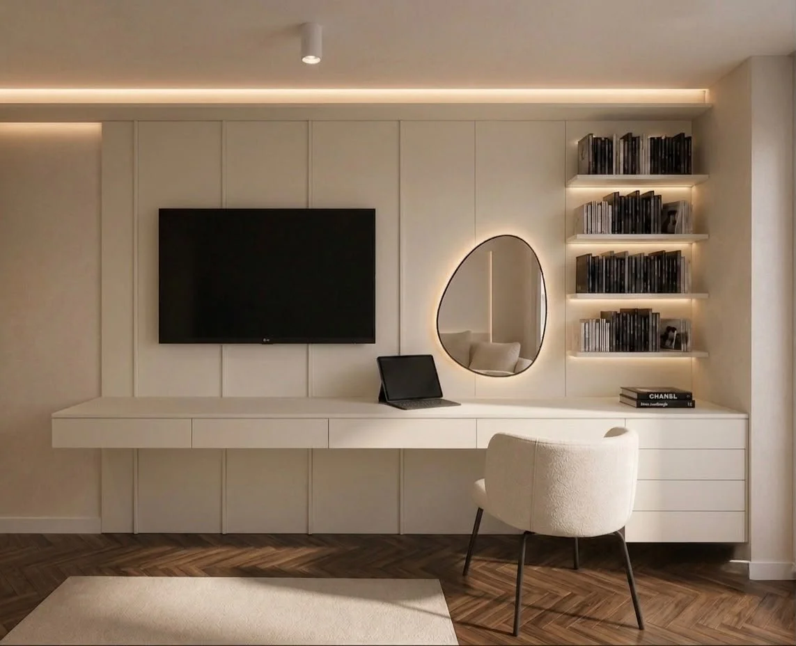 La parete attrezzata riunisce scrivania, cassetti, TV e libreria in un’unica composizione. Lo specchio organico retroilluminato introduce un elemento morbido, mentre le mensole illuminate creano profondità e valorizzano libri e oggetti.