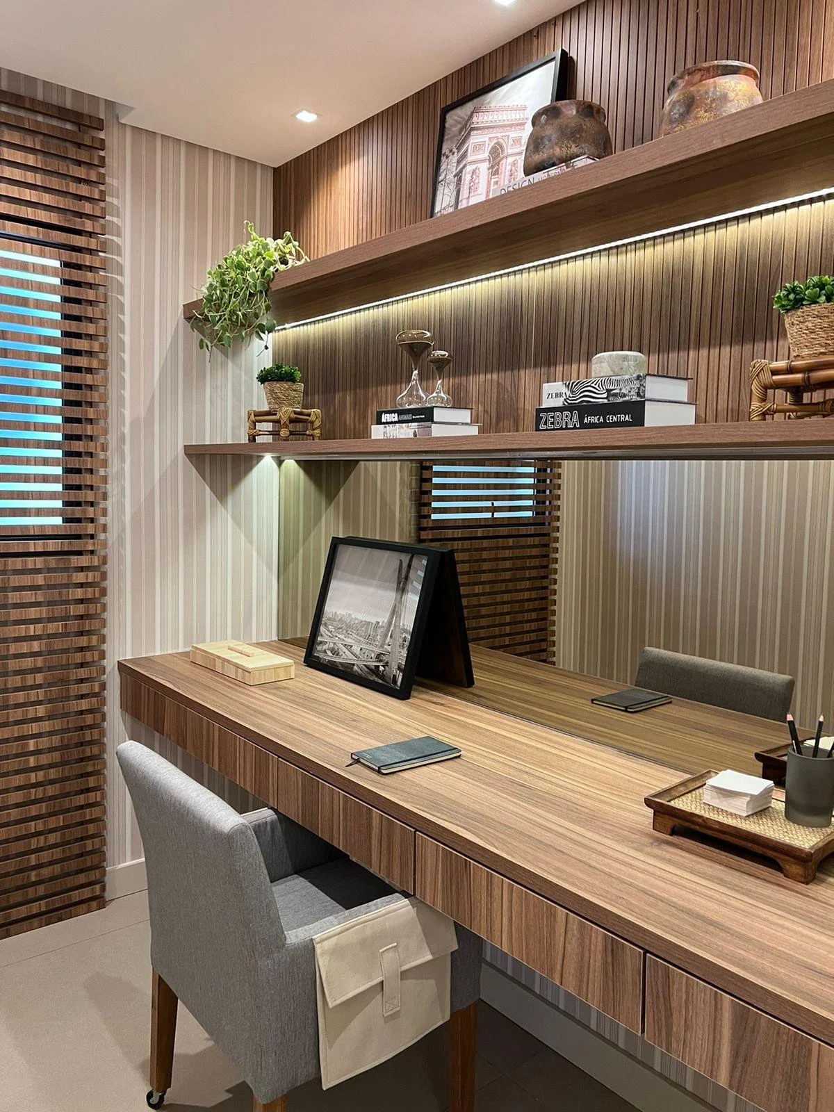 Zona ufficio con scrivania in legno e mensole per libri e decorazioni. 