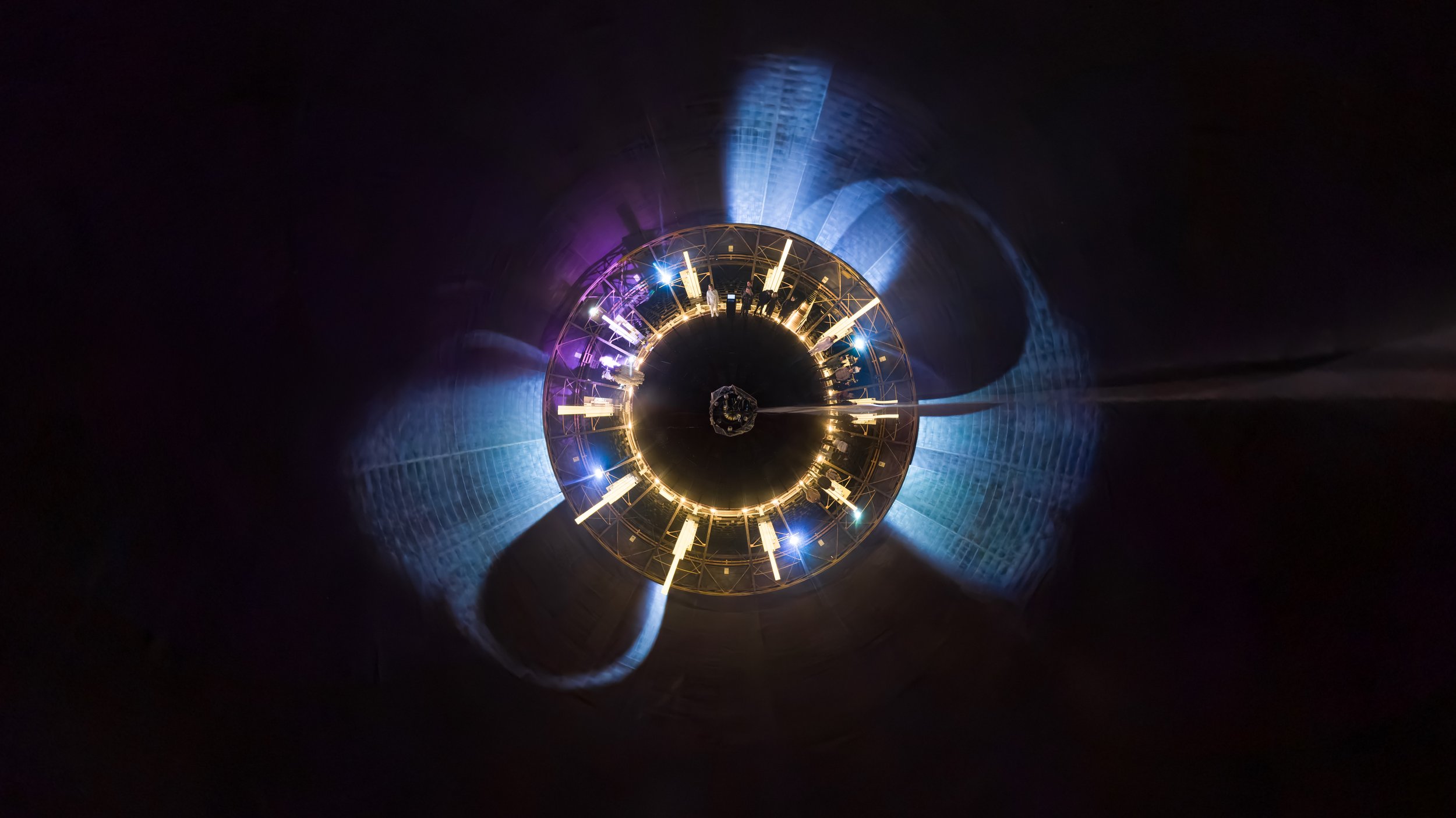 Abstract 360° projection inside a gasometer with dynamic light trails and immersive visual patterns surrounding the audience.