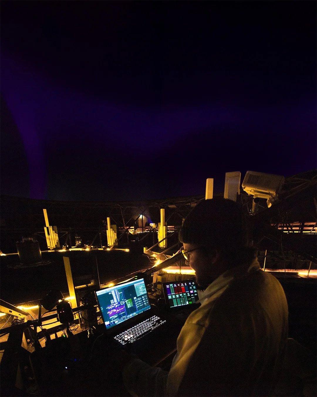 Michael Gamböck working inside the historic gas tank in Augsburg on his projections for ORPHEO. He is sourrounded by his laptop, a tablet an other technical equipment.