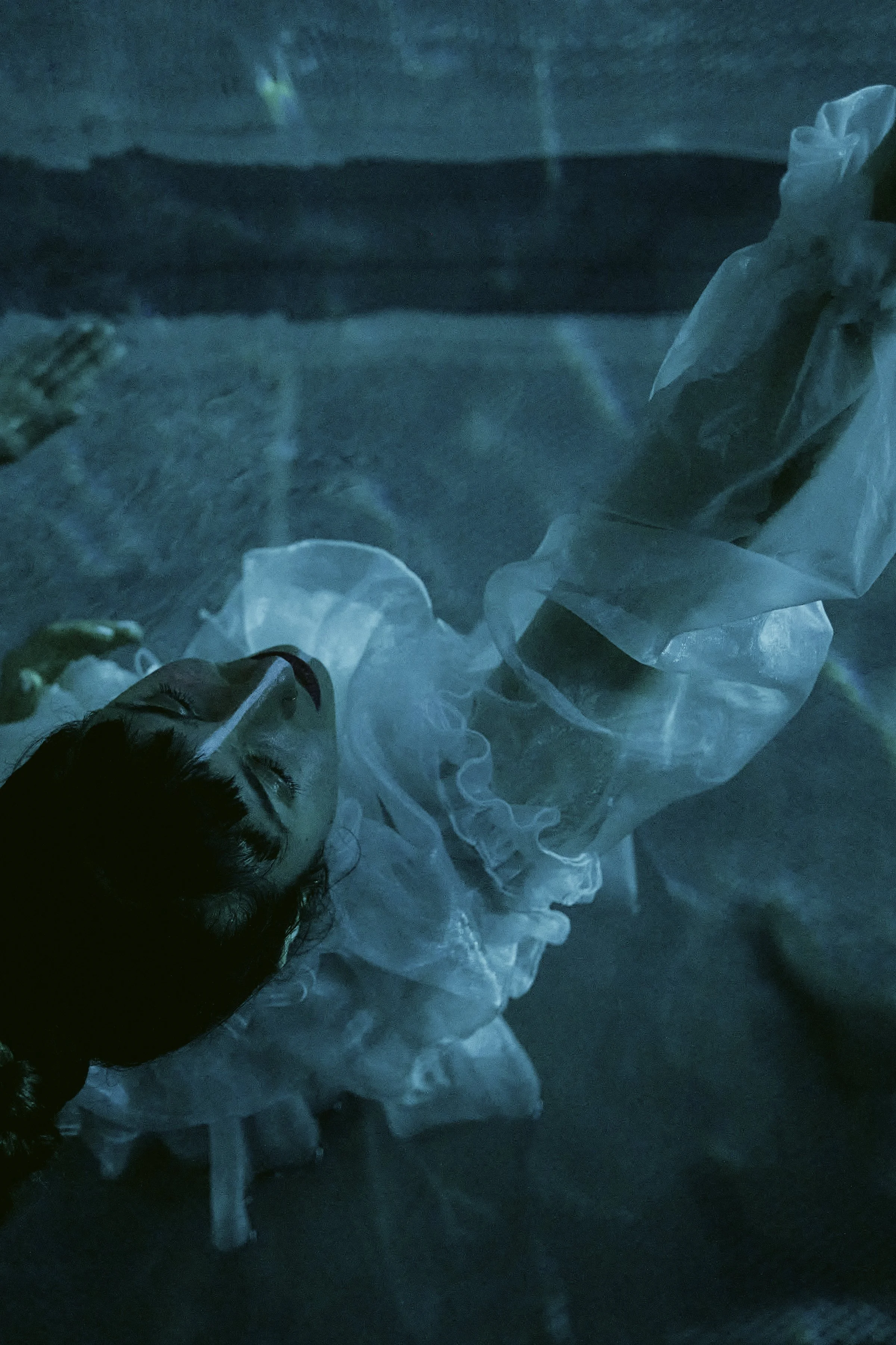 Performer floating in water during the Lichtmess theatre performance, illuminated by mystical blue light in a historic bathhouse.