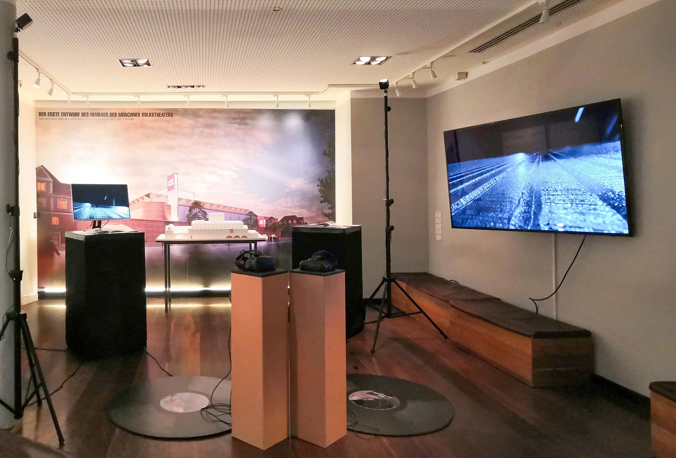 Installation view of ECHO – a sonicsphere at NetzKongress with two screens showing visuals, VR headsets placed on wooden pedestals, and large vinyl records on the ground.