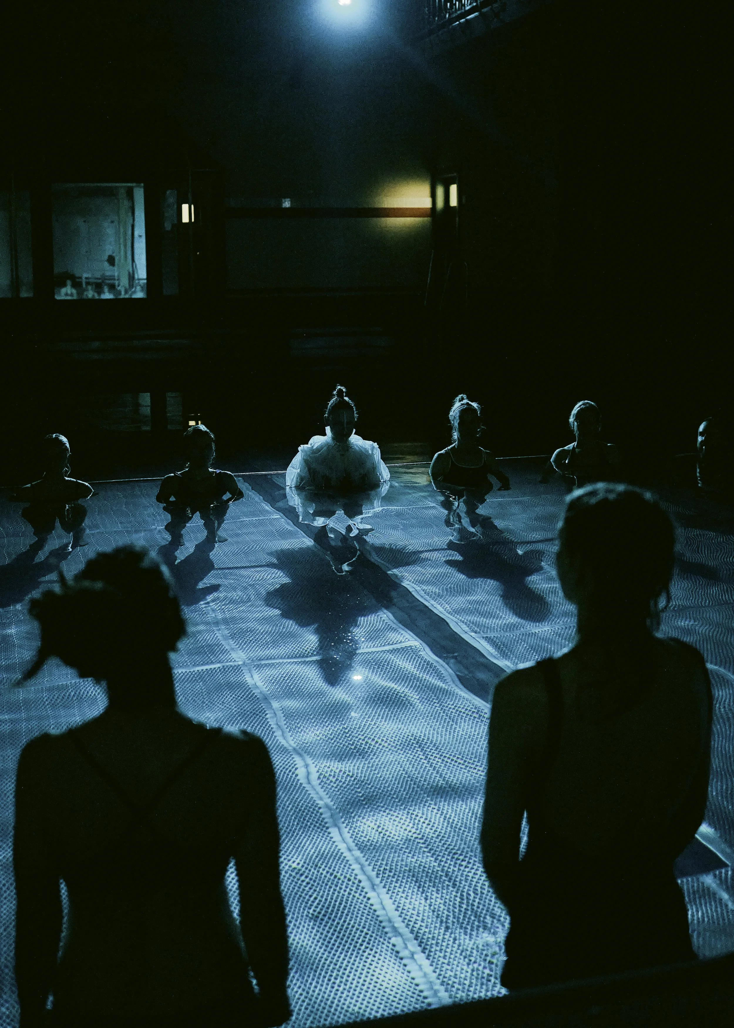 Audience and performer immersed in water at the Lichtmess theatre performance, illuminated by atmospheric, mystical light in a historic bathhouse setting.