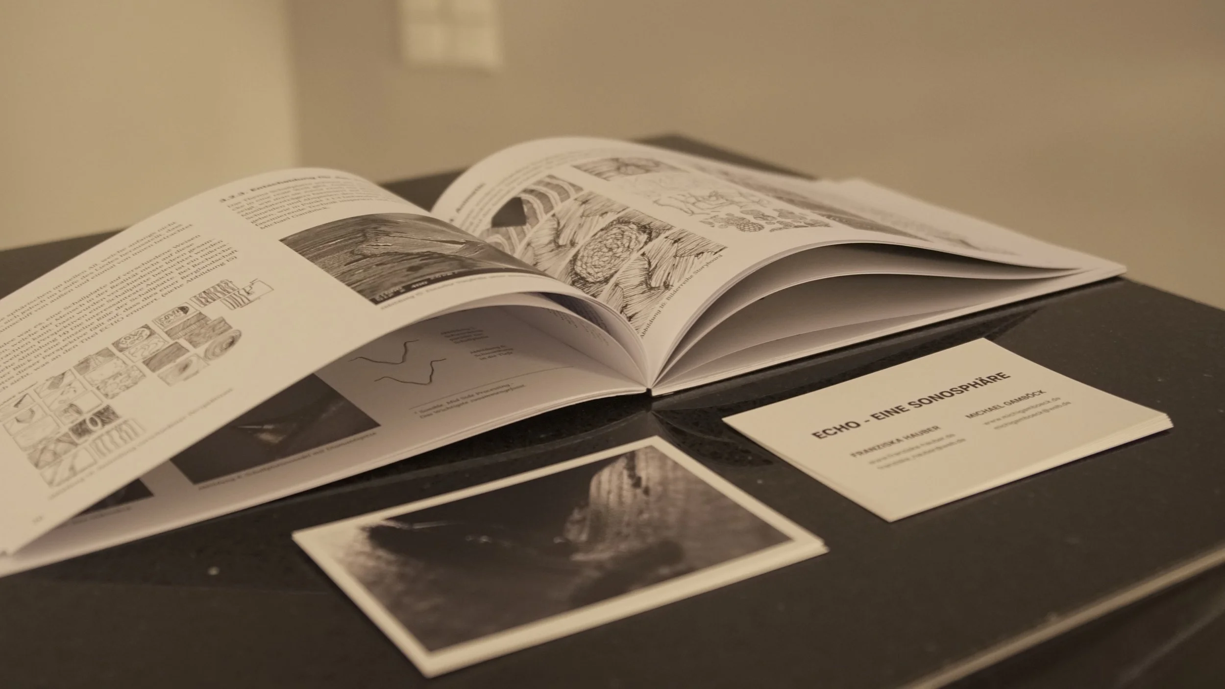 Open printed bachelor thesis of Michael Gamböck on a dark surface with a small photograph and a printed card titled 'ECHO - EINE SONOSPHÄRE'.