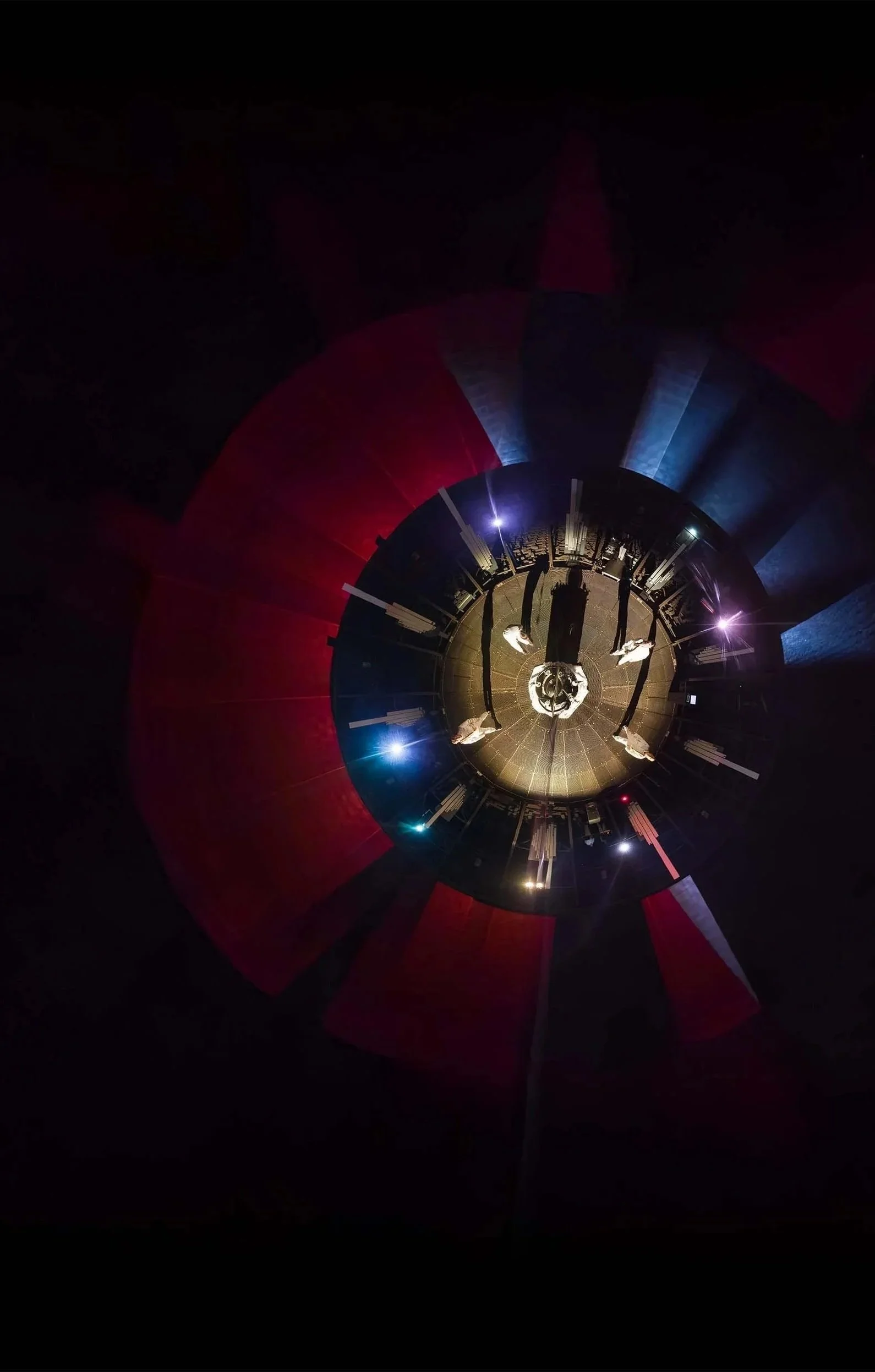 A panoramic, fisheye view of a fashion show runway with models walking, illuminated by bright stage lights, and a dark background.