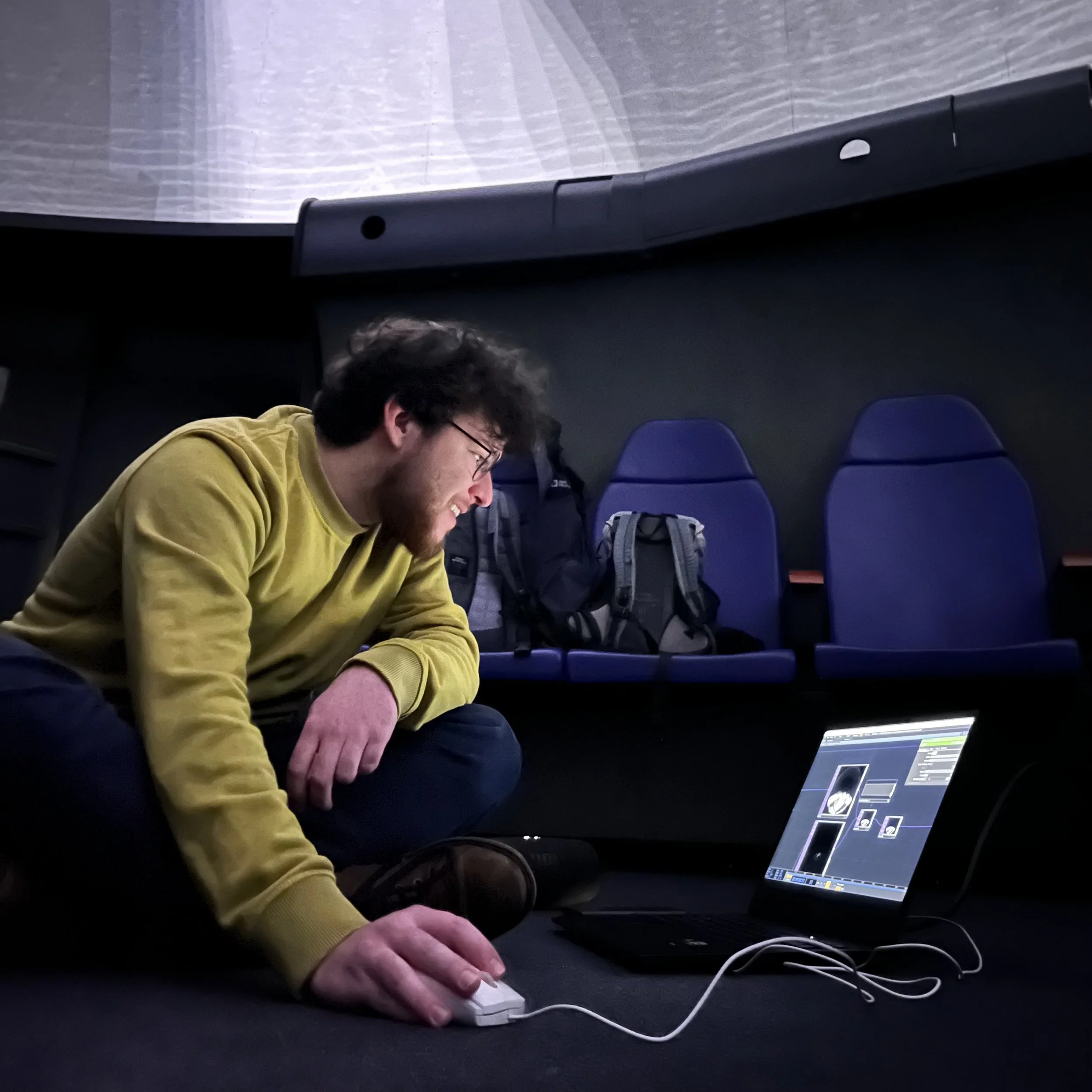 Michael Gamböck sitting in the planetarium Augsburg. He is testing new visuals with his laptop connected with the dome projectos.