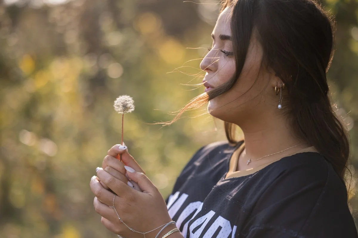 senior portrait blowing out a dandelion wish