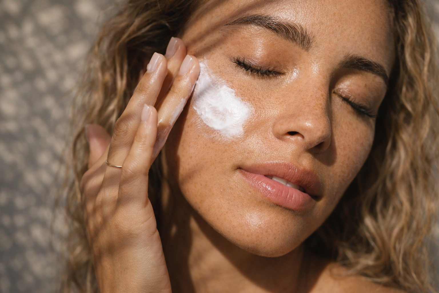 kvinde der bruger solcreme, Daily Defense SPF 50 på kinden.