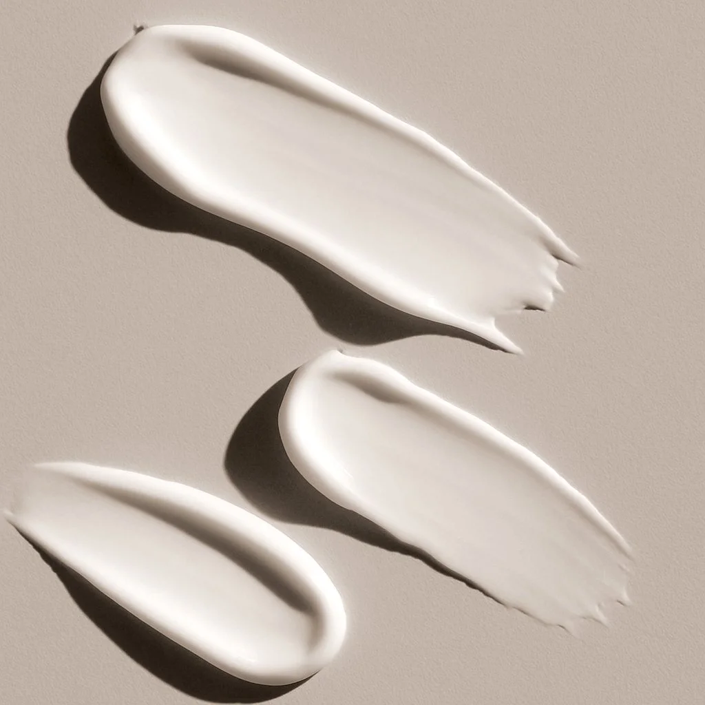 Three white ceramic spoons placed on a beige surface with shadows.
