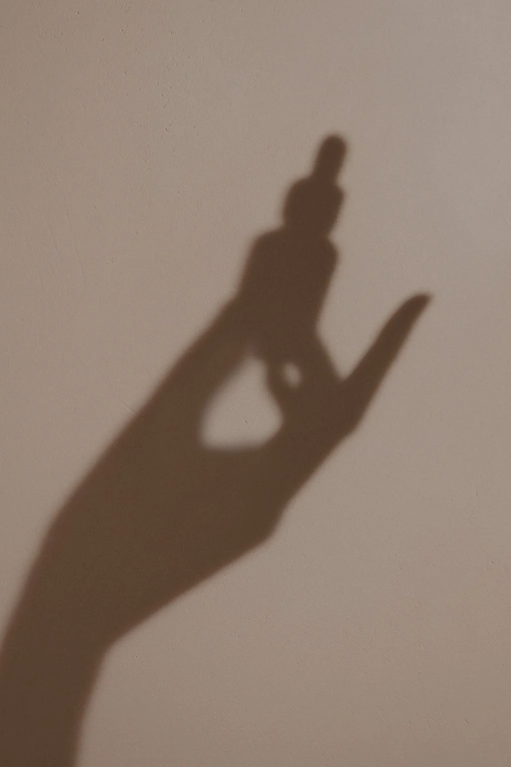 Shadow of a hand making an 'OK' gesture on a wall.