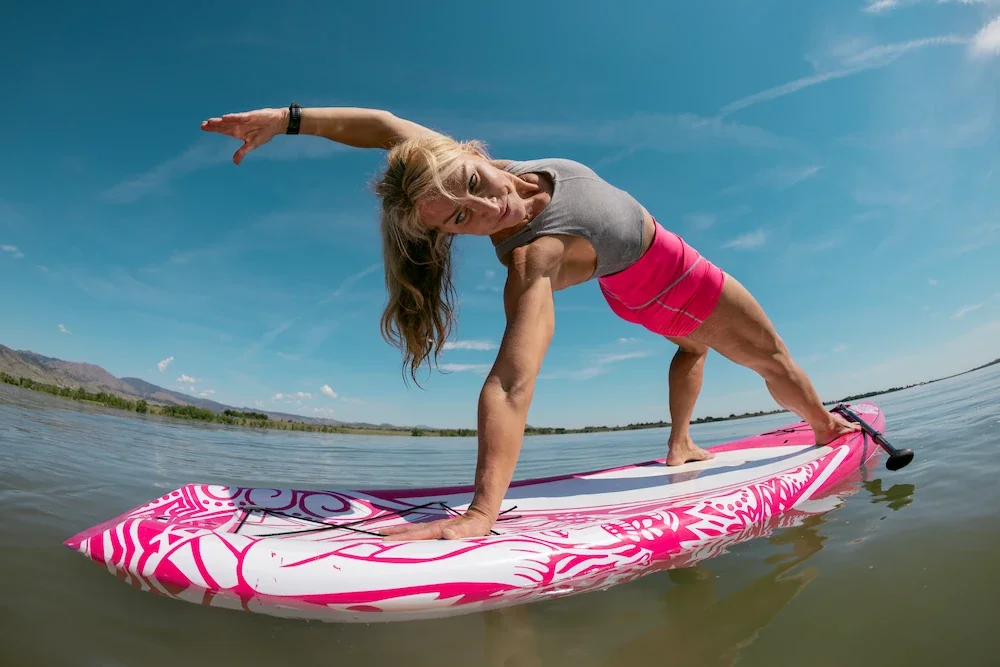 Lisa Fierer practicing yoga on a paddleboard on a calm lake.