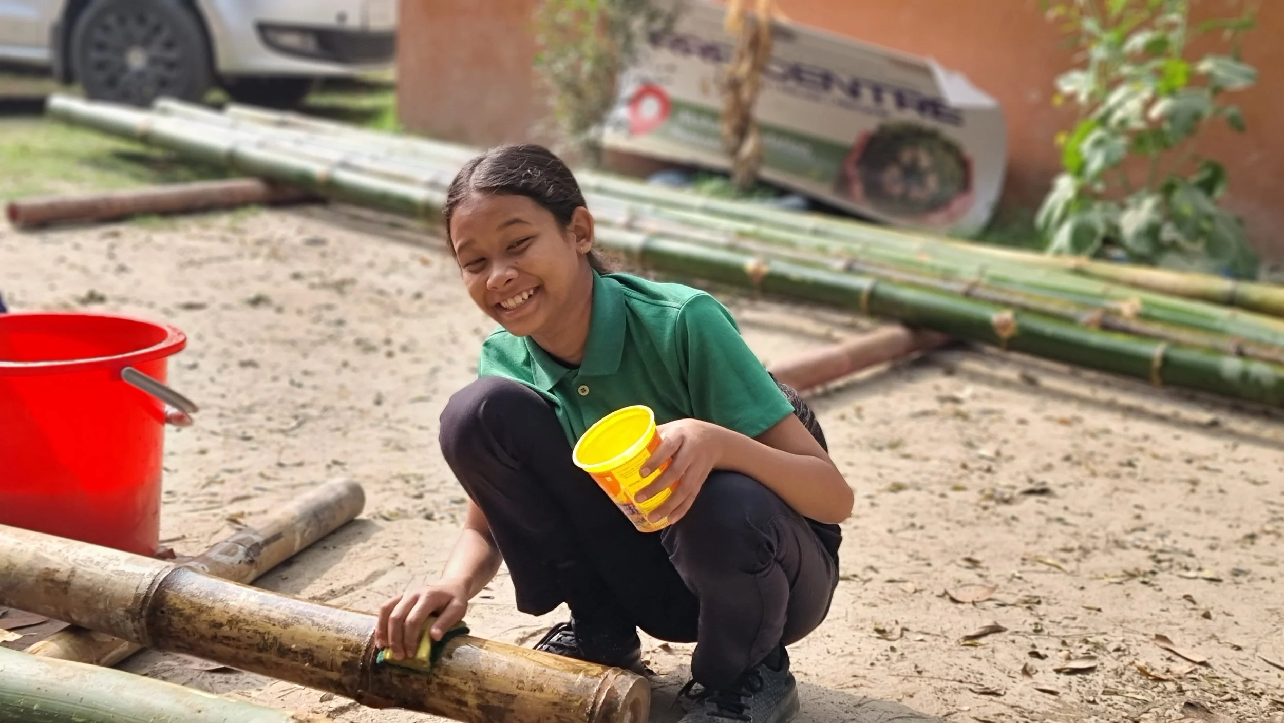 Smiling woman with curly hair and glasses in a cozy, well-lit indoor space.