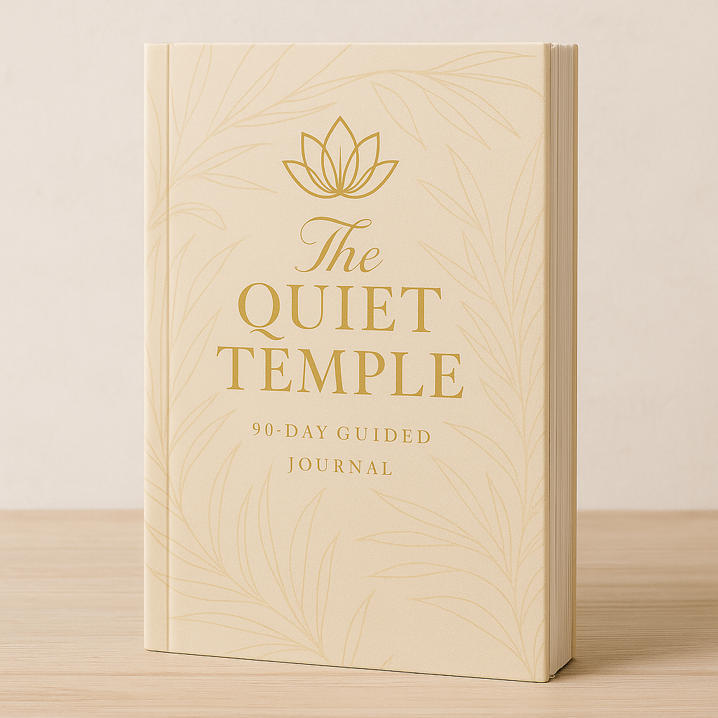 A beige hardcover guided journal titled 'The Quiet Temple' with gold text and a lotus flower logo on the cover, leaning against a plain light-colored wall on a wooden surface.