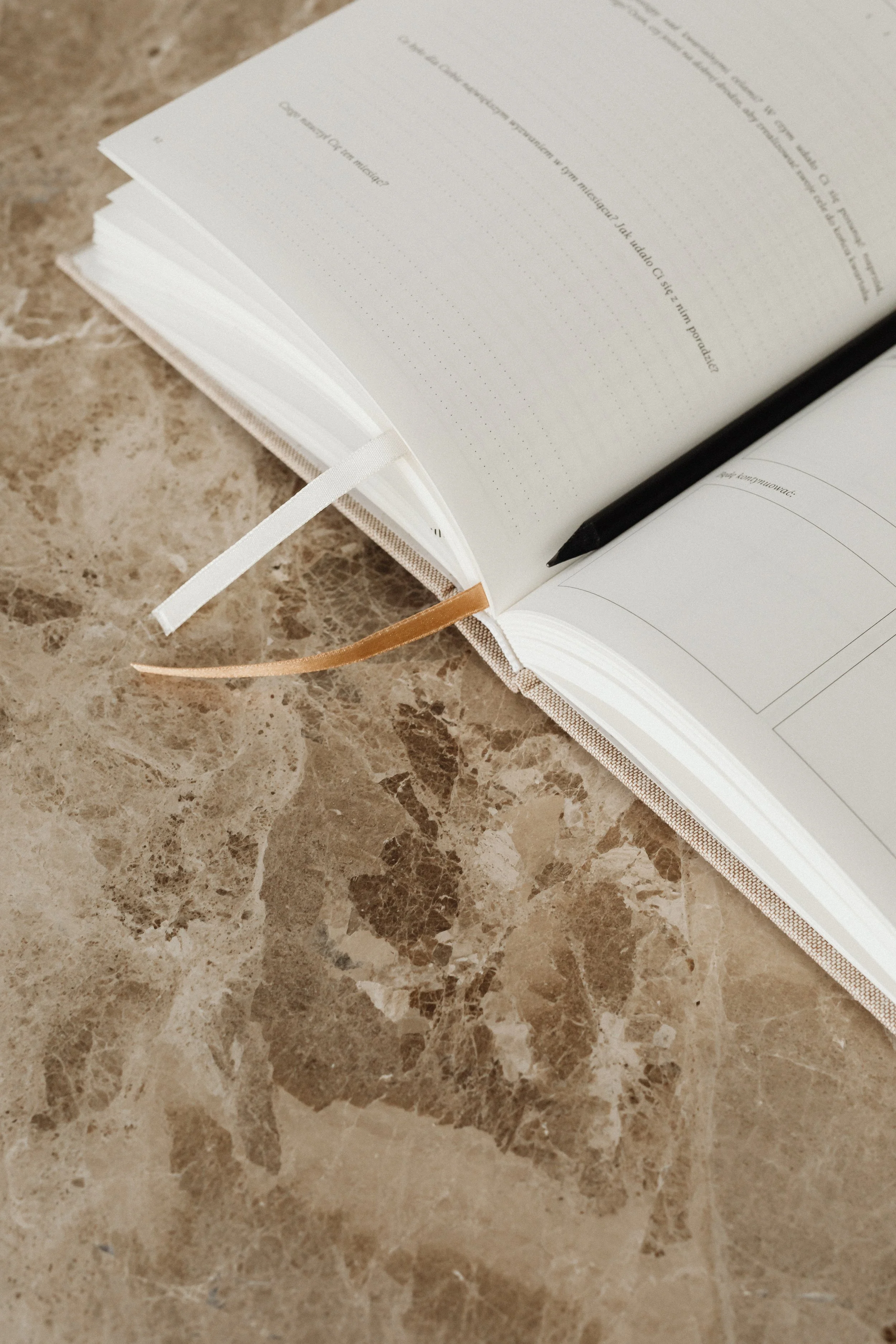 Open notebook with a black pen on a marble surface.