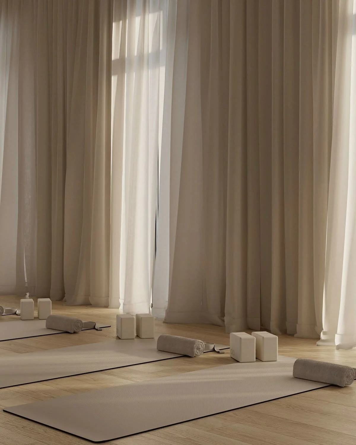 Salle de yoga avec tapis, serviettes, blocs et coussins, près de grandes fenêtres avec rideaux blancs.