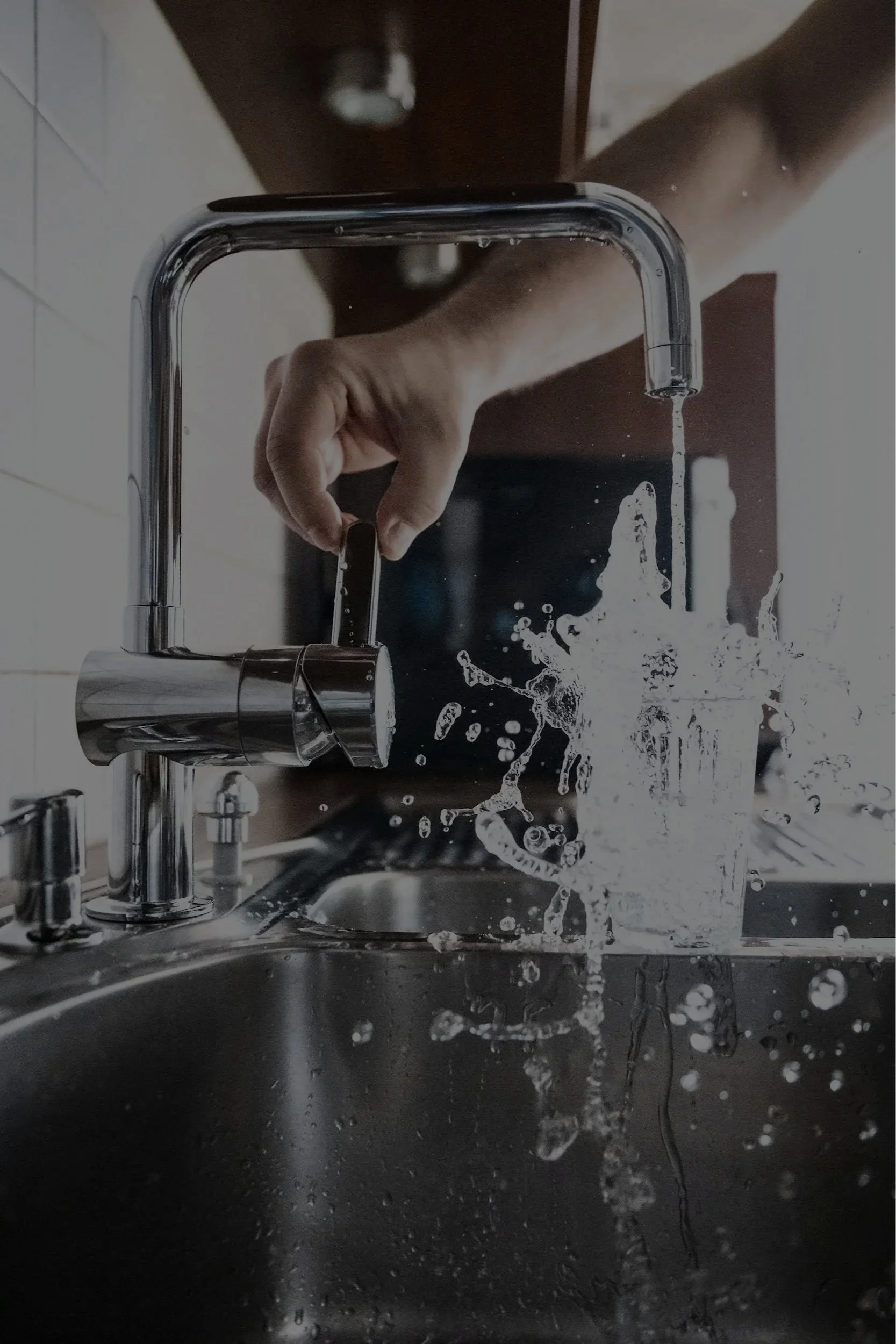 Person turning on a kitchen faucet, water splashing into the sink.