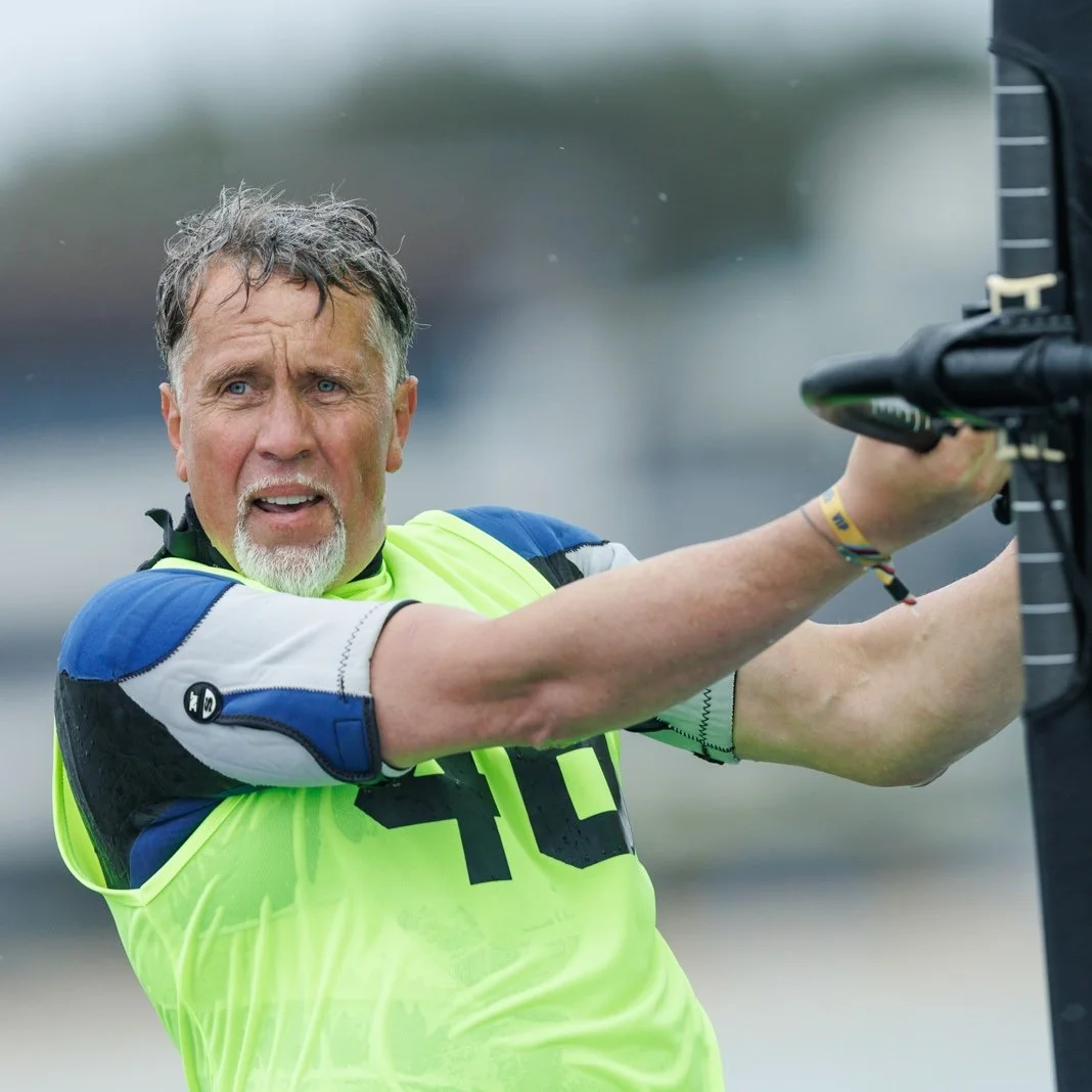 A man in a neon yellow and blue sports jersey with the number 10, struggling to hold onto a black motorcycle or scooter.