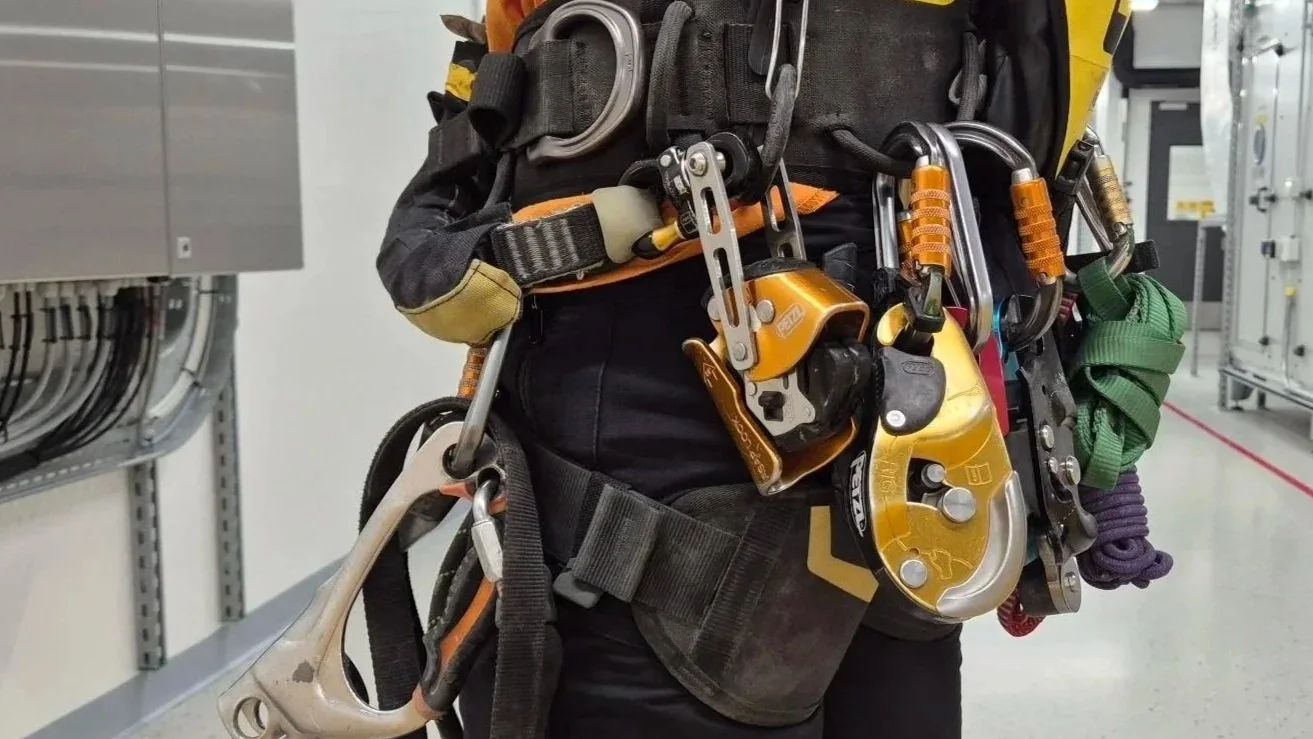 Nahaufnahme eines Kletterers mit Sicherheitsausrüstung, einschließlich Karabiner, Seil und Klettergurt.