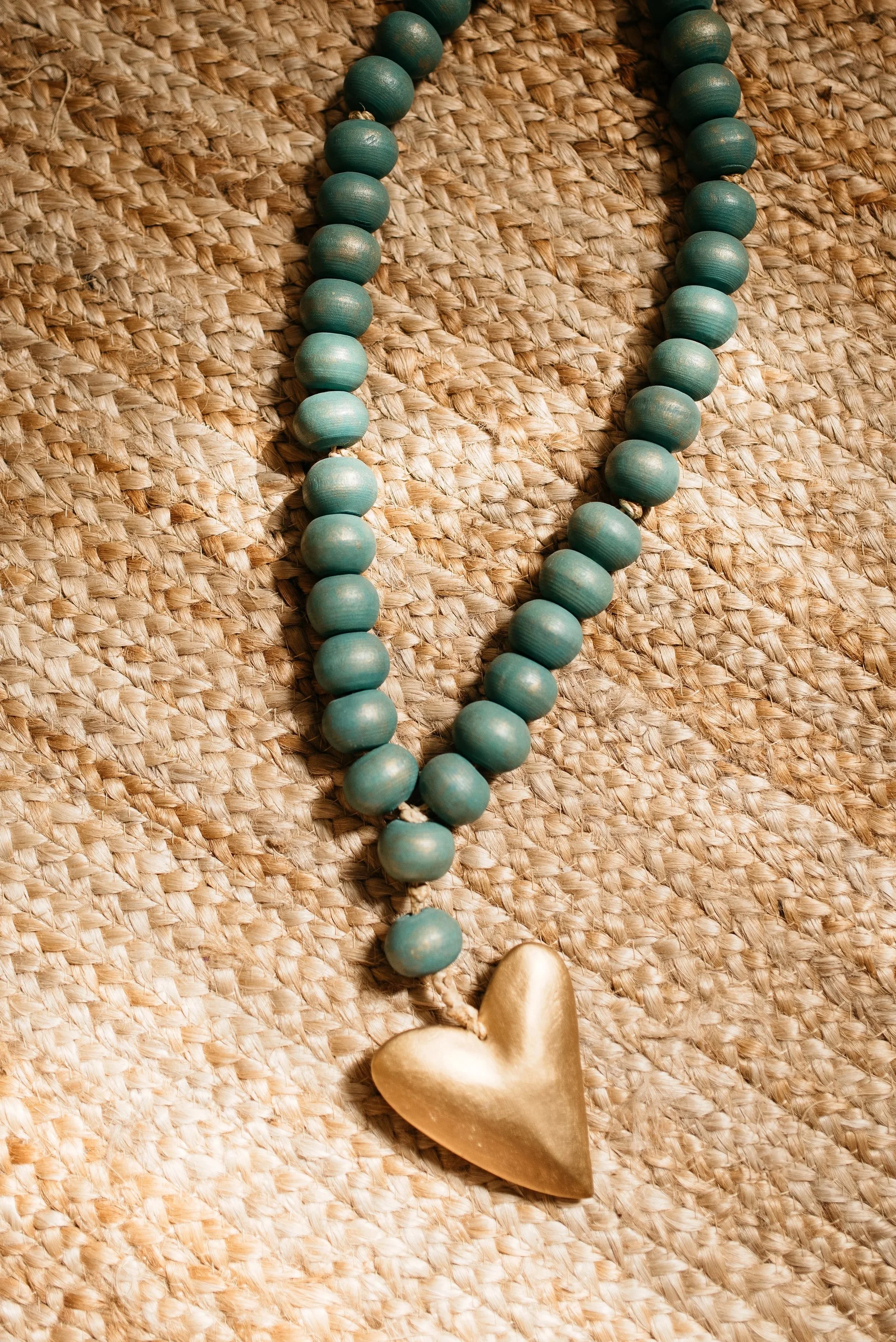 Handcrafted wooden heart on a strand of blue beads, displayed in the Heart Minding Therapy office in Austin — a quiet symbol of relational healing and care.