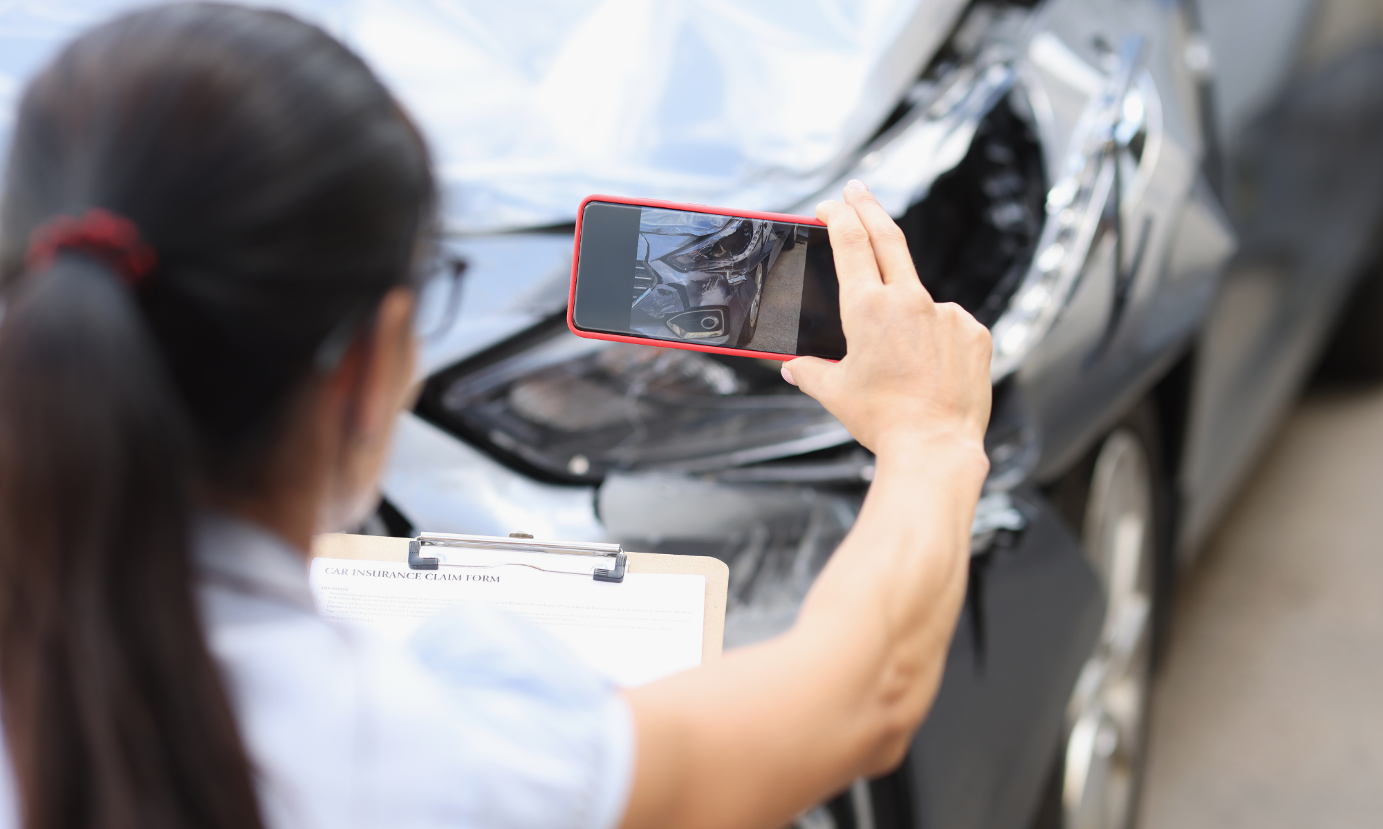 Driver taking photos of vehicle damage and intersection details for an insurance claim after a Phoenix accident