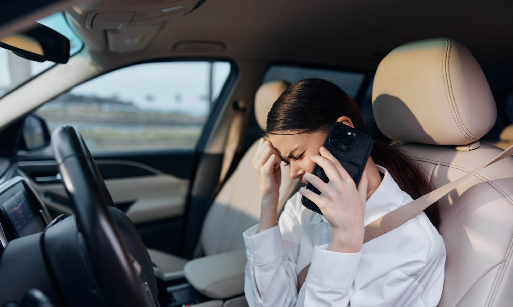Phoenix driver on phone after a car accident, deciding whether to call an accident helpline or an attorney.