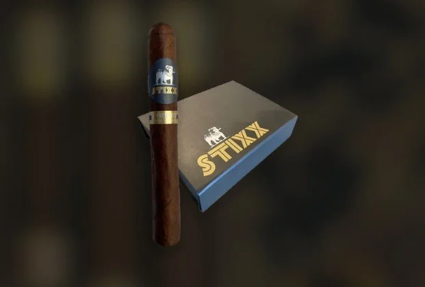 A cigar and a box of S TINX cigars on a dark surface.