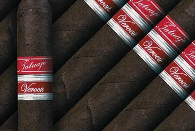 Multiple cigars with red and silver bands, labeled 'Tatuaje Verocu,' laid out on a dark surface.