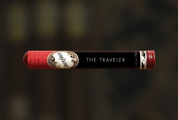 Book titled 'The Traveler' by Backstory, lying horizontally on a dark reflective surface.