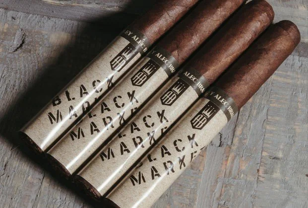 Four cigars with branded bands resting on a wooden surface.